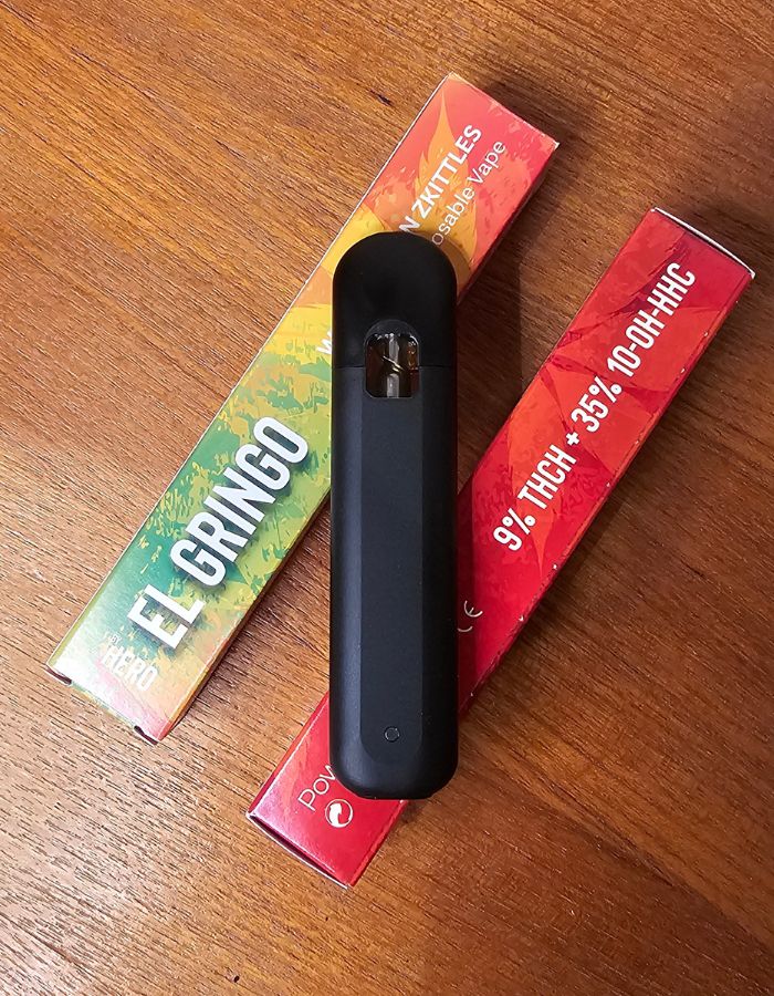 En svart engångsvape vilar på två förpackningar THCH vapes från El Gringo