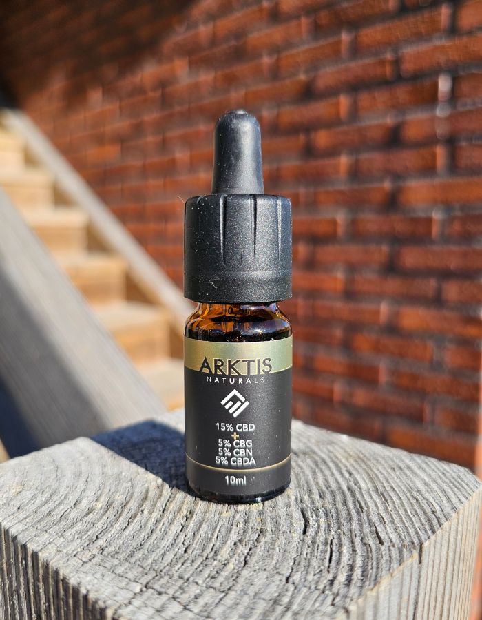 Arktis Naturals CBD + CBG, CBN, CBDA 30% står på en trästolpe med en tegelvägg i bakgrunden.